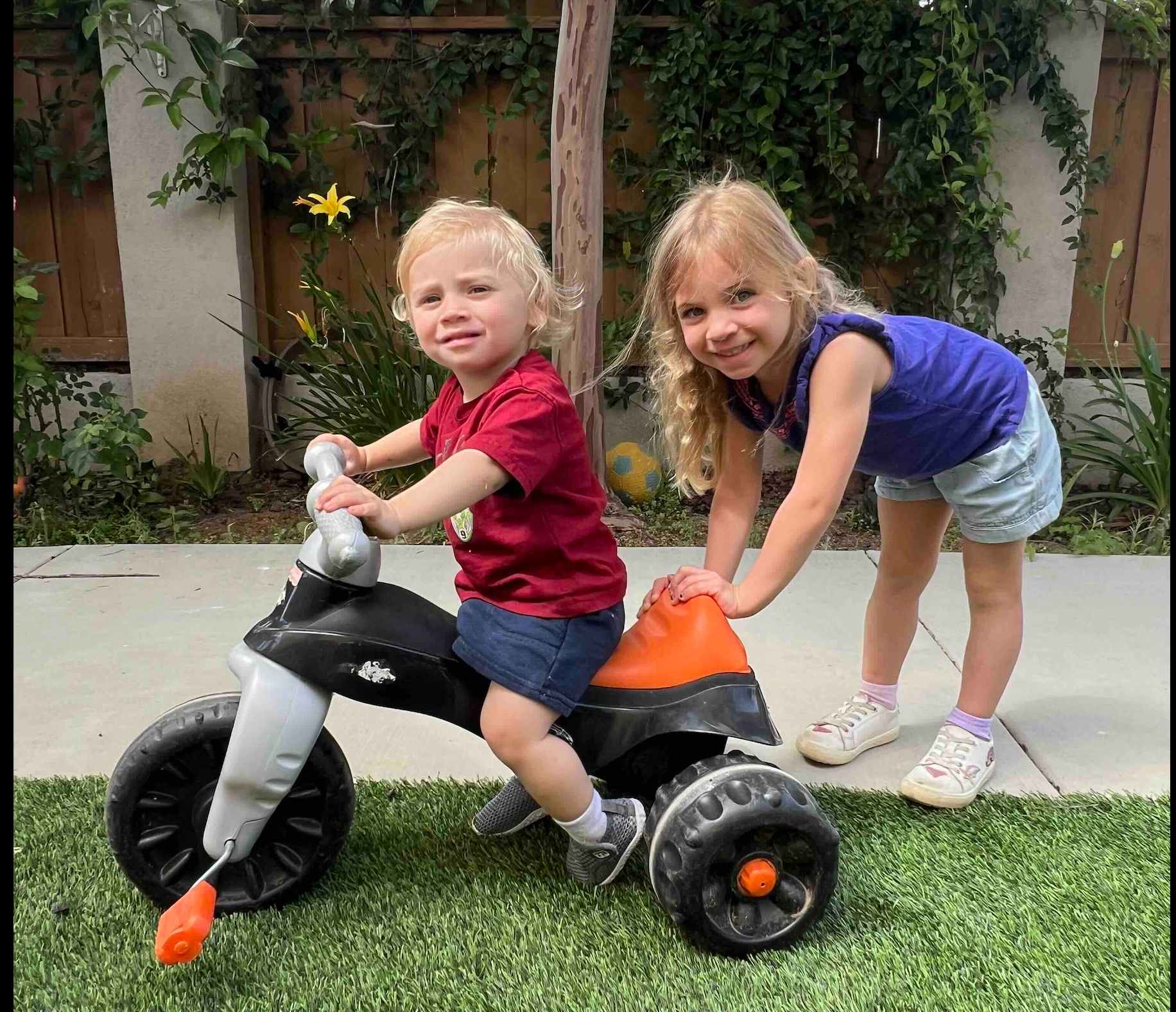 Children riding tricycles on the concrete bike path in the backyard at Ms. Rena's Preschool in Escondido, California